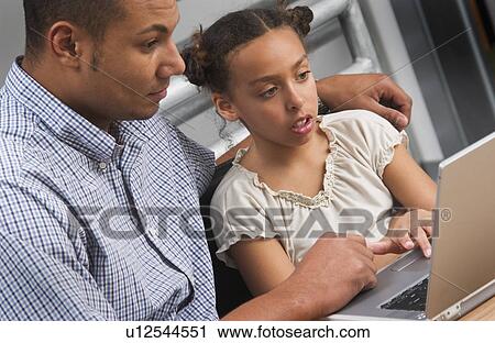 Stock Image - African American father helping daughter with homework. Fotosearch