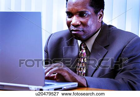 Stock Photo - African American man working on laptop. Fotosearch