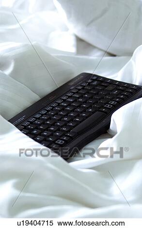 Stock Photography - Black keyboard on a bed. Fotosearch