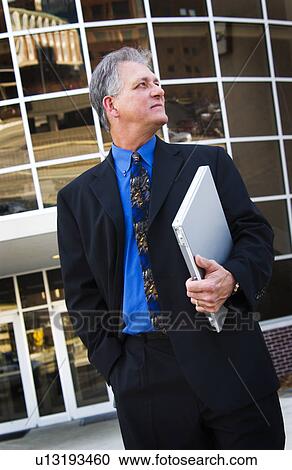 Stock Image - Businessman holding laptop. Fotosearch