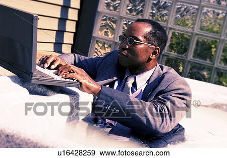 Businessman on laptop in a hot tub View Large Photo Image Stock Photo - Businessman on laptop in a hot tub. Fotosearch