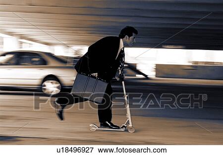 Stock Photo - Businessman on scooter in parking lot. Fotosearch