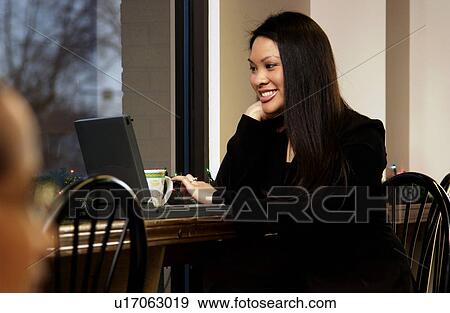 Stock Photo - Businesswoman working on laptop in restaurant. Fotosearch