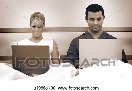 Couple in bed working on laptop computers View Large Photo Image Stock Image - Couple in bed working on laptop computers. Fotosearch
