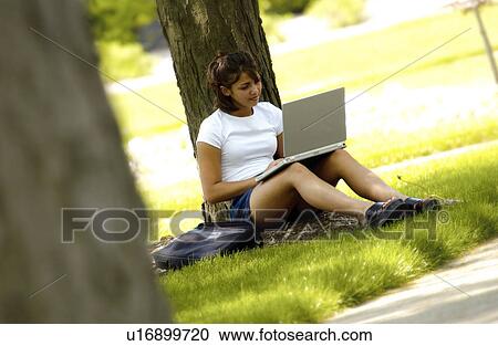 Stock Image - Girl studying under tree. Fotosearch