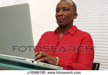 Stock Image - Older woman working on a laptop. Fotosearch
