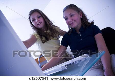 Stock Image - Two girls at computer. Fotosearch