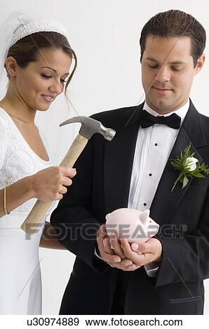 Stock Photo - Bride and groom breaking piggy bank. Fotosearch
