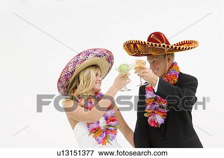 Stock Photo - Bride and groom wearing sombreros and flower leis and toasting. Fotosearch