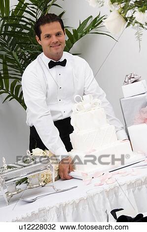 Stock Image - Server setting wedding cake on table. Fotosearch
