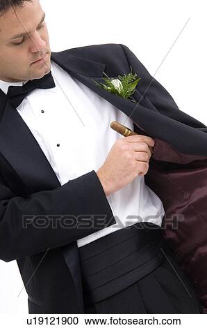 Stock Image - Man putting cigar inside his suit jacket. Fotosearch