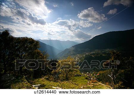 Stock Image - Countryside view with sunlight through clouds. Fotosearch