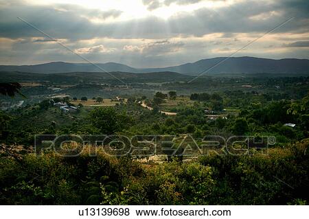 Stock Photo - Countryside view with sunlight through clouds. Fotosearch
