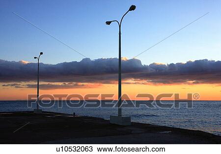 Stock Image - Lamp posts in front of sunset sky. Fotosearch