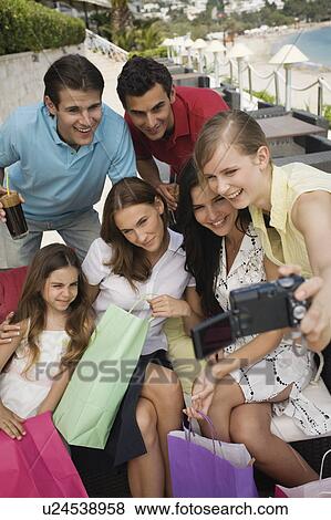 Group of friends with shopping bags taking photo View Large Photo Image Stock Photo - Group of friends with shopping bags taking photo. Fotosearch