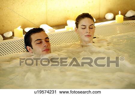 Stock Image - One man with one woman in jacuzzi at a spa. Fotosearch
