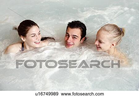 Stock Photo - One man with two women in jacuzzi at a spa. Fotosearch