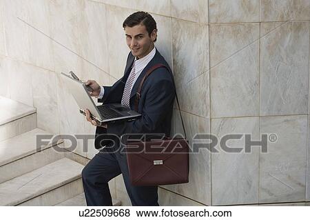 Businessman holding laptop and cell phone View Large Photo Image Stock Photo - Businessman holding laptop and cell phone. Fotosearch