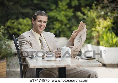 Stock Photography - Businessman in garden cafe with newspaper. Fotosearch