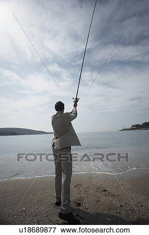 Stock Photo - Businessman on beach fishing. Fotosearch