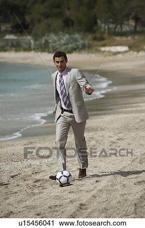 Stock Image - Businessman on beach playing soccer. Fotosearch