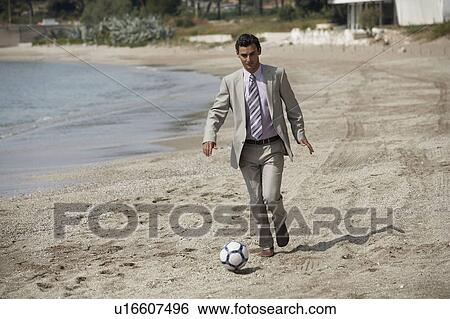 Stock Photograph - Businessman on beach playing soccer. Fotosearch