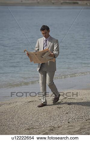 Picture - Businessman on beach reading a newspaper. Fotosearch