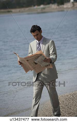 Businessman on beach reading a newspaper View Large Photo Image Stock Photo - Businessman on beach reading a newspaper. Fotosearch