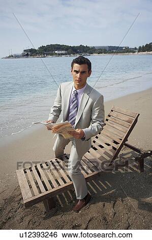 Stock Photograph - Businessman on beach with a newspaper. Fotosearch