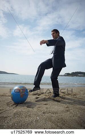 Stock Photo - Businessman on beach with globe beach ball. Fotosearch