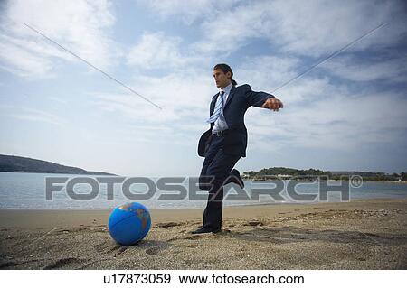 Businessman on beach with globe beach ball View Large Photo Image Stock Photo - Businessman on beach with globe beach ball. Fotosearch