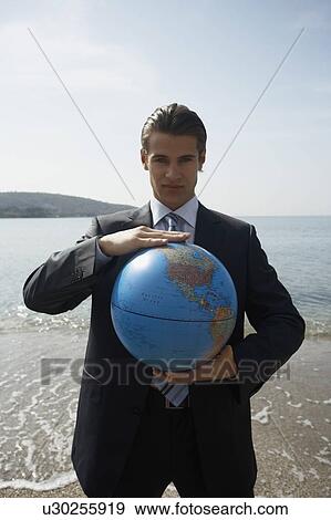 Stock Photo - Businessman on beach with globe. Fotosearch
