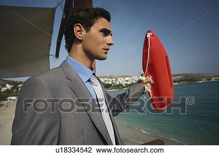 Businessman on life guard stand with life preserver View Large Photo Image Stock Image - Businessman on life guard stand with life preserver. Fotosearch