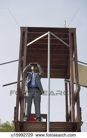 Stock Photo - Businessman on life guard stand with binoculars. Fotosearch