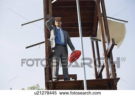 Stock Photography - Businessman on life guard stand with life preserver. Fotosearch