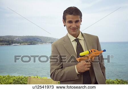 Stock Image - Businessman with plastic water gun. Fotosearch