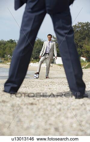 Stock Photograph - Businessmen on beach playing soccer. Fotosearch