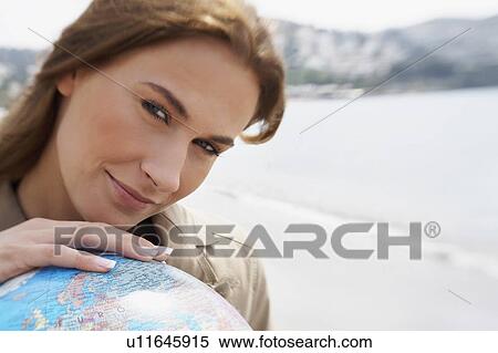 Stock Photography - Businesswoman on beach with globe. Fotosearch