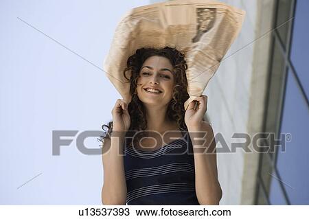 Stock Image - Happy businesswoman with newspaper on head. Fotosearch
