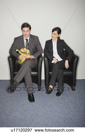 Male office worker with flowers sitting next to female colleague View Large Photo Image Stock Photo - Male office worker with flowers sitting next to female colleague. Fotosearch