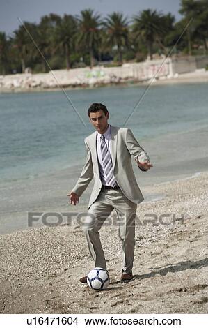 Picture - Businessman on beach playing soccer. Fotosearch