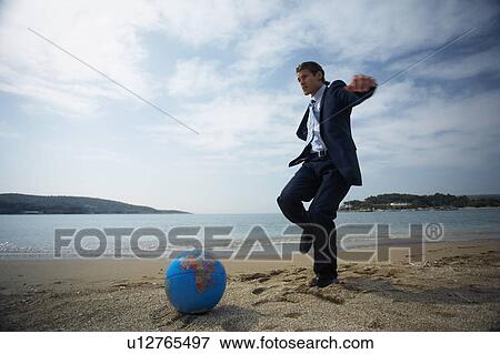Businessman on beach with globe beach ball View Large Photo Image Stock Photo - Businessman on beach with globe beach ball. Fotosearch