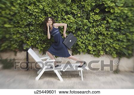 Stock Image - Businesswoman running on chaise lounge. Fotosearch