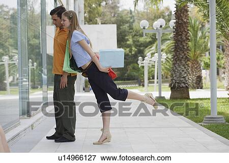 Stock Photo - Couple with shopping bags looking at shop window. Fotosearch