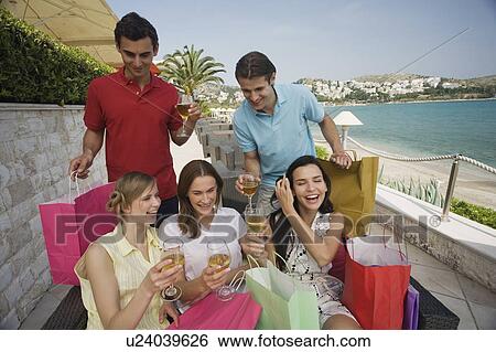 Stock Photograph - Group of friends with shopping bags and wine. Fotosearch
