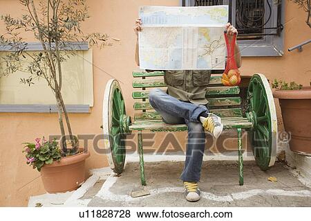 Stock Photo - Man on bench reading a map. Fotosearch