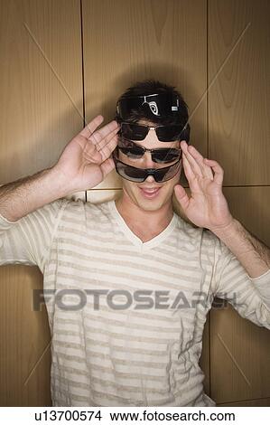 Picture - Man trying on several sunglasses in store. Fotosearch
