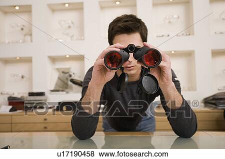 Stock Photo - Man with binoculars in eyeglass store. Fotosearch