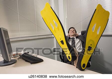 Stock Photo - Office worker at desk wearing swim flippers. Fotosearch