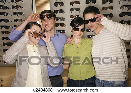 Two couples posing with sunglasses in store View Large Photo Image Stock Image - Two couples posing with sunglasses in store. Fotosearch
